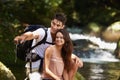 Couple, point and backpack for hiking in jungle with smile for thinking, holiday and search by river. Man, woman and bag Royalty Free Stock Photo