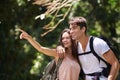 Couple, point and smile for hiking in jungle with sign for thinking, holiday and happy on path. Man, woman and bag for Royalty Free Stock Photo