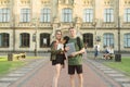 Couple of positive happy students standing at college entrance holding notebooks, books and laptop. Two cheerful attractive young Royalty Free Stock Photo