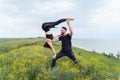 Couple practicing acro yoga poses outdoors outside. Pair of sportsmen acrobats showing flexibility class workout. Athlete holding