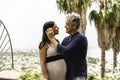 Couple, with pregnant woman, looking into each other`s eyes and posing for a photo during summer vacation in the esotic garden -