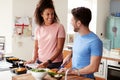 Couple Preparing Batch Of Healthy Meals At Home In Kitchen Together