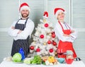 Couple preparing a healthy meal together for christmas dinner. Man and woman chef apron santa hat near christmas tree Royalty Free Stock Photo