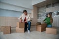 Couple preparing for transportation to new flat. Wife packing belongings and husband sealing boxes