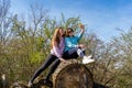 couple of pretty friendly women taking a selfie with smartphone sitting on pile of logs