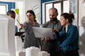 Couple of professional architects holding laptop looking at blueprints next to colleagues Royalty Free Stock Photo