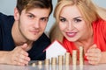 Couple Protecting House Model With Stacked Coins