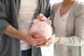 Couple putting coin into piggy bank, closeup. Money savings concept