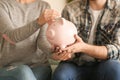 Couple putting coin into piggy bank, closeup. Money savings concept