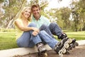 Couple Putting On In Line Skates In Park