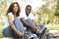 Couple Putting On In Line Skates In Park