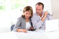 Couple reading construction plan and using laptop