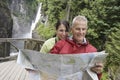 Couple Reading Map Against Waterfall Royalty Free Stock Photo