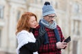 Couple reads message in smart-phone. Woman embraces man with cellular. Guy in hat and glasses received SMS. Royalty Free Stock Photo