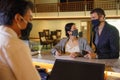 Couple and receptionist at counter in hotel wearing medical masks as precaution against virus. Couple on a business trip