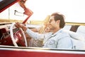 Happy couple driving in a red car at sunset Royalty Free Stock Photo