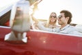 Smiling couple in a red car at sunset Royalty Free Stock Photo