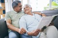 Couple, relax and reading book together on sofa in living room with love, care and quality time. Senior man, happy woman Royalty Free Stock Photo