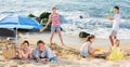 Couple relaxing on beach while their kids playing active games Royalty Free Stock Photo