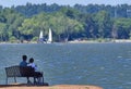 Couple relaxing on bench watching sailboats Royalty Free Stock Photo