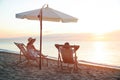 Couple relaxing on deck chairs at beach. Summer vacation Royalty Free Stock Photo