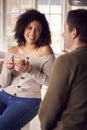 Couple Relaxing At Home Sitting At Kitchen Counter With Coffee
