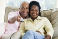 Couple relaxing in living room holding remote