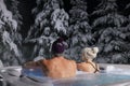 Couple relaxing in outdoor hot tub and enjoying snowy winter forest landscape at spa resort Royalty Free Stock Photo