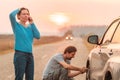 Couple repairing car flat tire on the road Royalty Free Stock Photo