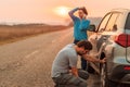 Couple repairing car flat tire on the road Royalty Free Stock Photo