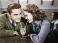 Couple in a restaurant looking at each other and sharing a milk shake with two straws Royalty Free Stock Photo