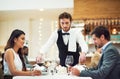 Couple, restaurant server and fine dining at table for valentines day date, bonding and romance in night. Man, woman and Royalty Free Stock Photo