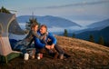 Couple resting in campsite in mountains at sunny autumn.