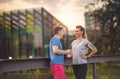 Couple resting after exercise in park - Man and woman training outdoors and having fun while resting during sunset on a sunny day Royalty Free Stock Photo