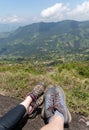 Couple resting in the top of a mountain showing their feet in front of a natural view