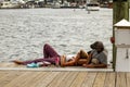 a couple resting on wooden board walk of the marina by the sea