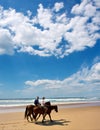 Couple of riders on beach under dramatic skies Royalty Free Stock Photo