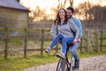 Couple Riding Bike Through Countryside With Woman Sitting On Handlebars
