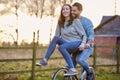 Couple Riding Bike Through Countryside With Woman Sitting On Handlebars