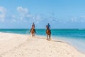 Couple riding on horseback along the sea