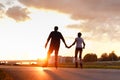 Couple riding on roller skates, holding hands on the street during sunset Royalty Free Stock Photo