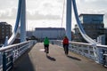 A couple riding their bikes over a modern bridge