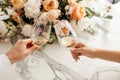 Couple on romantic date. Friends clinking glasses, top view. White wine, flowers around on marble table. Wedding celebration,