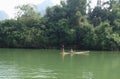 Couple rowing cross green clear river by bamboo simple boat