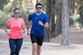 Couple of runners exercising in a park and listening to music Royalty Free Stock Photo
