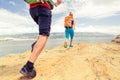 Couple runners running with backpacks on rocku trail at seaside