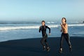 Couple Running On Beach. Handsome Man And Sexy Woman In Fashion Sporty Outfit Jogging Along Ocean Coast. Royalty Free Stock Photo