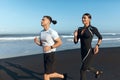 Couple Running On Beach. Handsome Man And Sexy Woman In Fashion Sporty Outfit Jogging Along Ocean Coast In Morning. Royalty Free Stock Photo