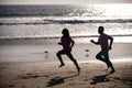 Couple running on beach. Silhouette of young man and woman running jogging along the sea. Royalty Free Stock Photo