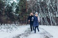 Couple running in winter forest together. People having fun outdoors. Man and woman laughing Royalty Free Stock Photo